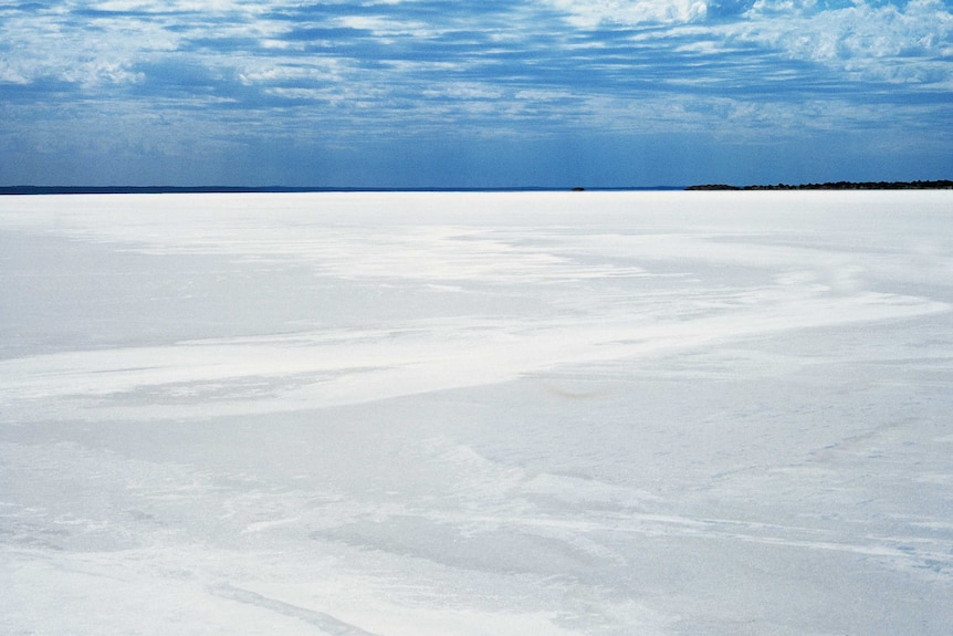 An oceanic salt lake under a cloudy blue sky.
