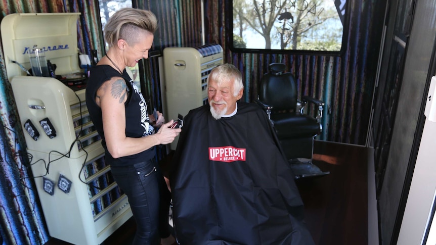 Danielle Hannah gives a man a haircut in a mobile barbershop