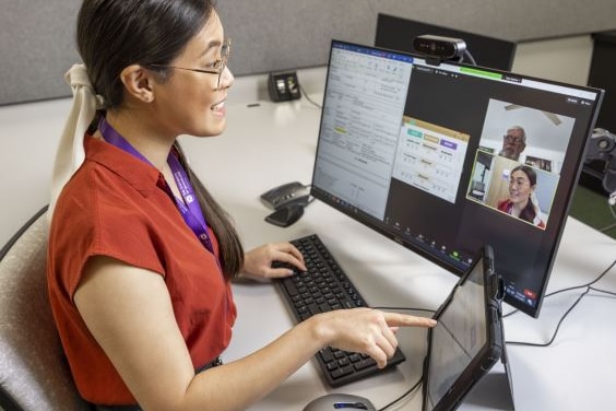 Women talks to a person through a computer telehealth session.