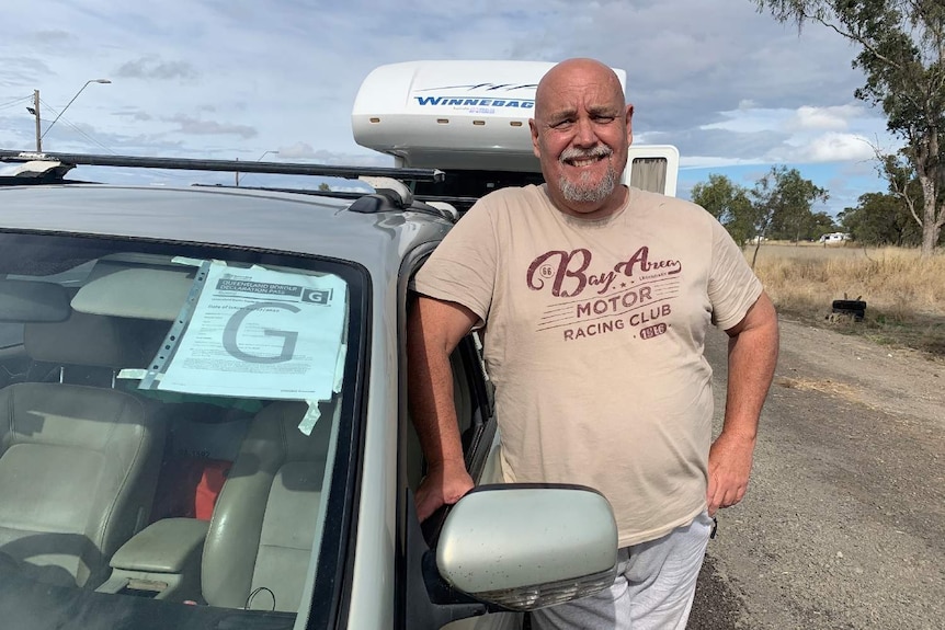 Craig Dixon leans on his silver car in a queue at the Goondiwindi checkpoint.