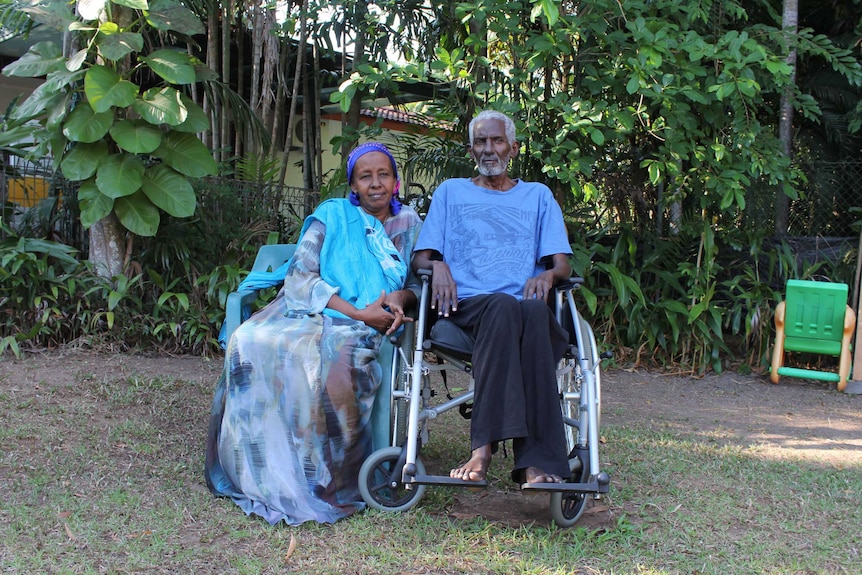 A woman in traditional Somali dress sits next to her husband in a leafy green Darwin backyard.