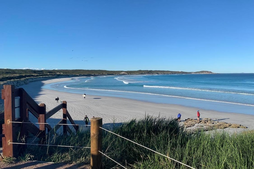 A picture of an Esperance beach, near Twilight Beach. A surfer walks on the sand and kids play