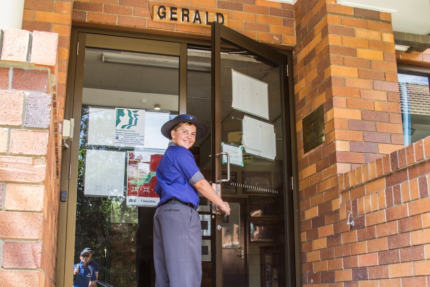 School boy standing by a glass door