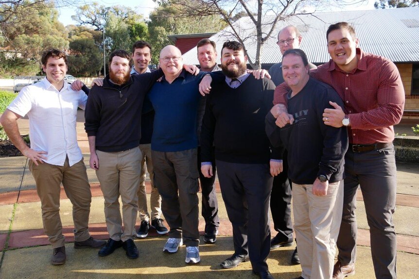 Melville Primary School's male teaching staff stand together smiling in the school grounds.