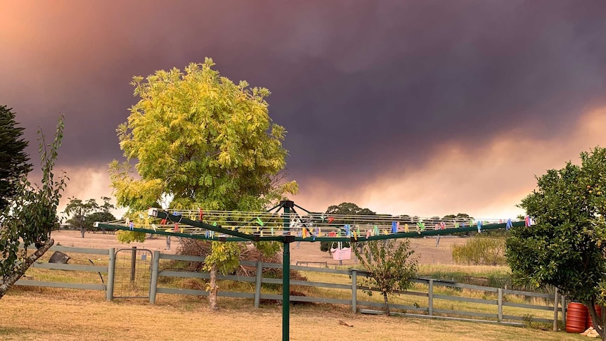smoke in the sky behind a backyard and clothesline