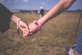 Two women holding hands at a music festival.