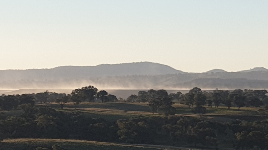 Dust blows in the wind in a long-distance shot of a dam.