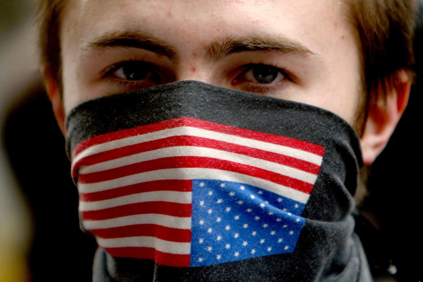 A young man with an American flag bandana over his mouth