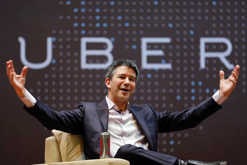 Uber CEO Kalanick speaks to students during an interaction at IIT campus in Mumbai with his arms in the air with the Uber sign.