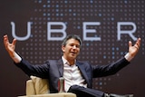 Uber CEO Kalanick speaks to students during an interaction at IIT campus in Mumbai with his arms in the air with the Uber sign.