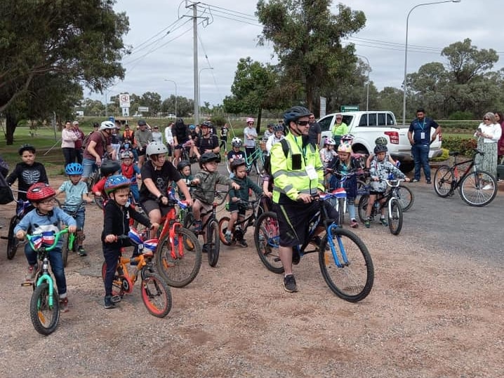 A group of people all ages on bicycles waiting to set off on a fundraising ride. 