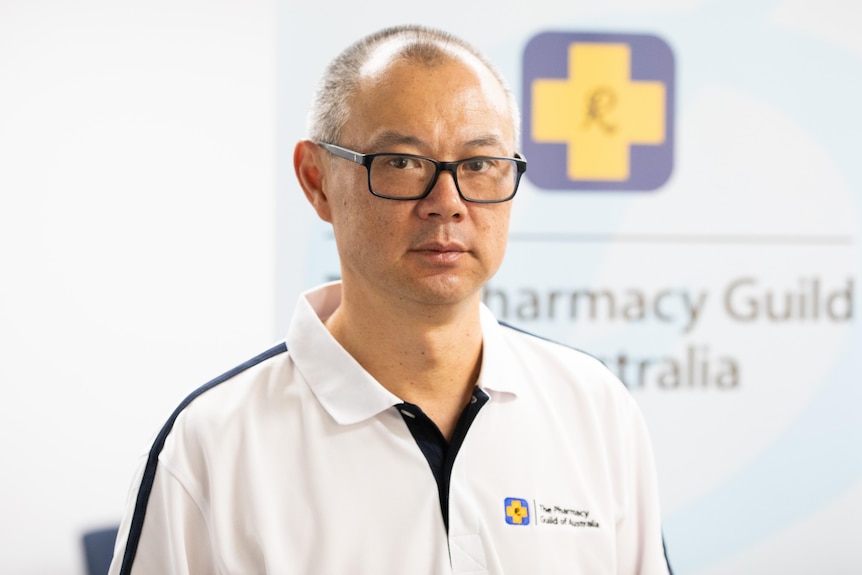 Andrew Ngeow standing in front of a Pharmacy Guild banner.