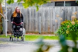 25-year-old Jasmine West walks her whippet Penny on a gravel path next to green grass and an agapanthus bush.