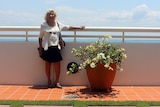 Audrey Grace stands next to a potplant