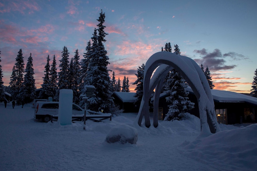 Ice hotel complex under a dark blue sky with pink clouds scattered throughout.