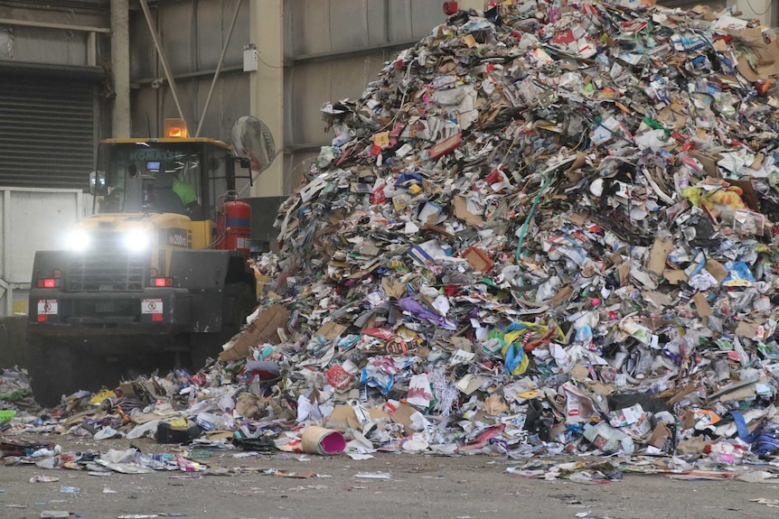 A truck shifts rubbish into a large stockpile.