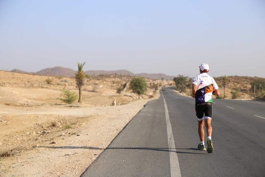 Pat Farmer running solo on a road through the desert of Rajasthan.