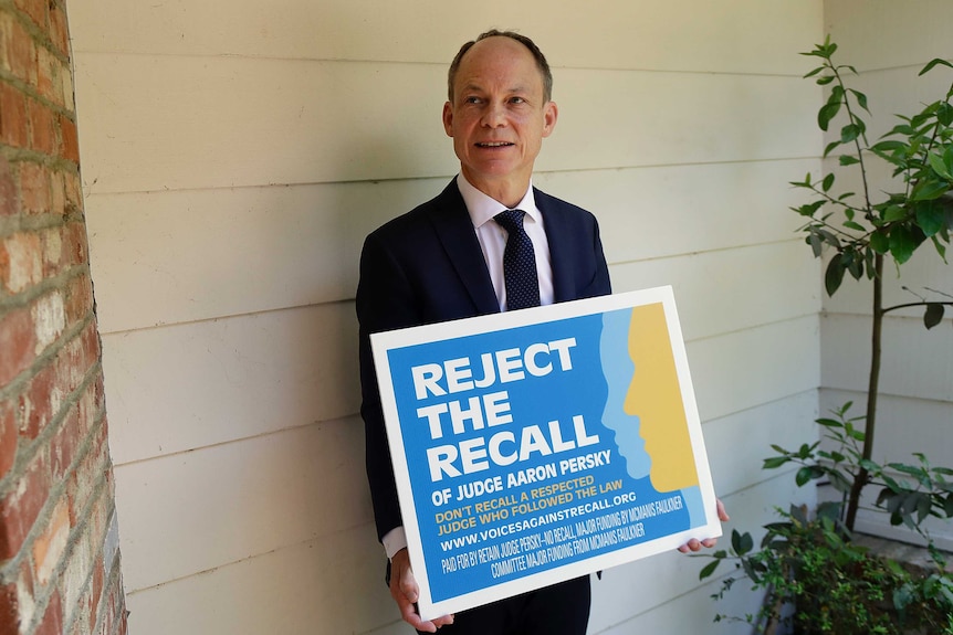 Aaron Persky holds a sign that reads: Reject the recall of Judge Aaron Persky.