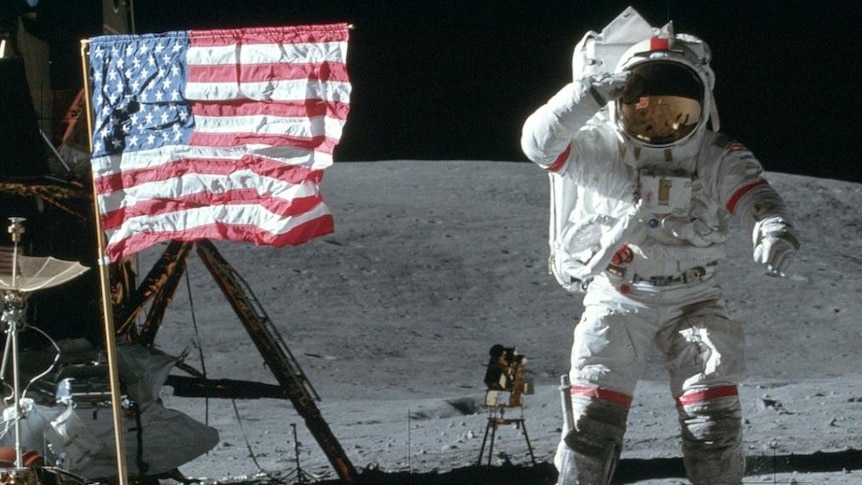 John Young jumping and saluting the moon next to the American flag.