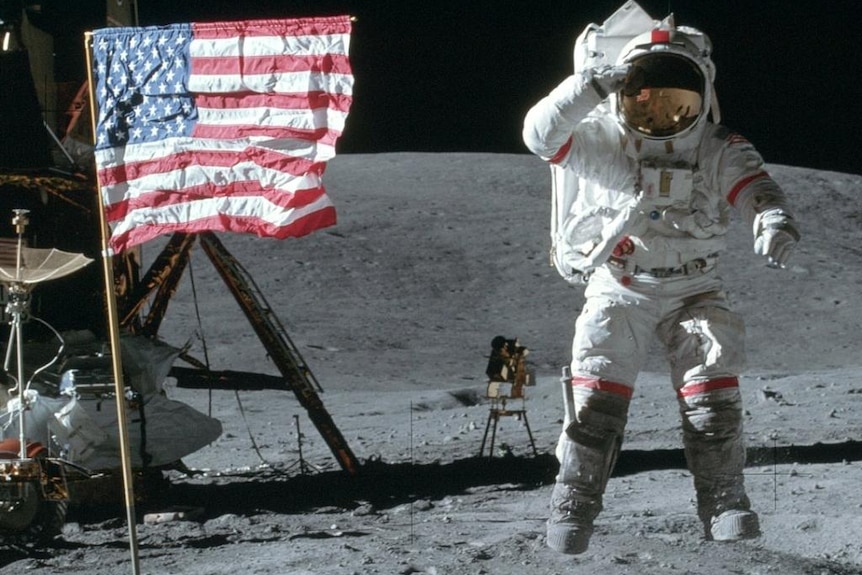 John Young jumping and saluting the moon next to the American flag.