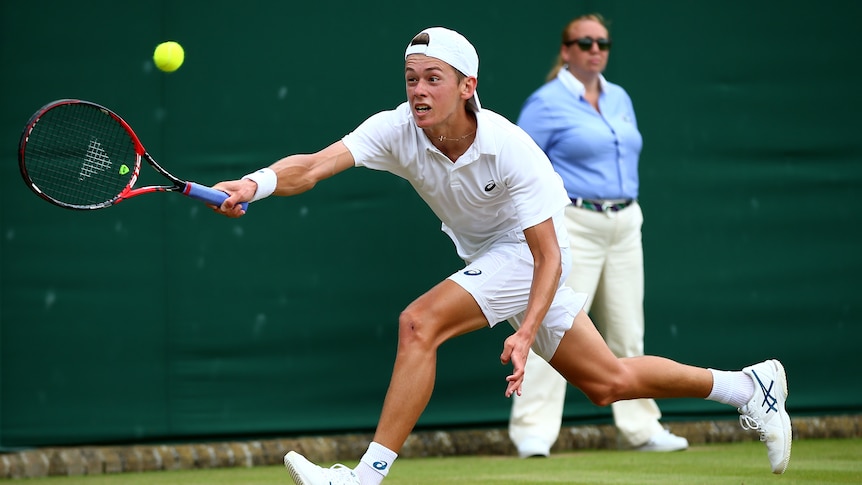 Alex De Minaur returns a shot at Wimbledon juniors