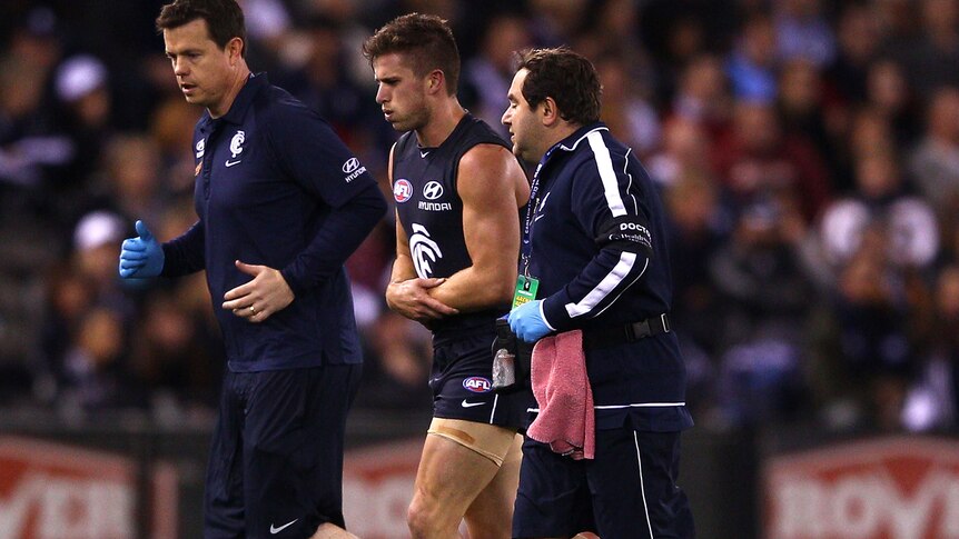 Carlton's Marc Murphy leaves the field against the Crows clutching his shoulder.