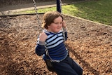 Jake Mitchell sitting on a park swing.