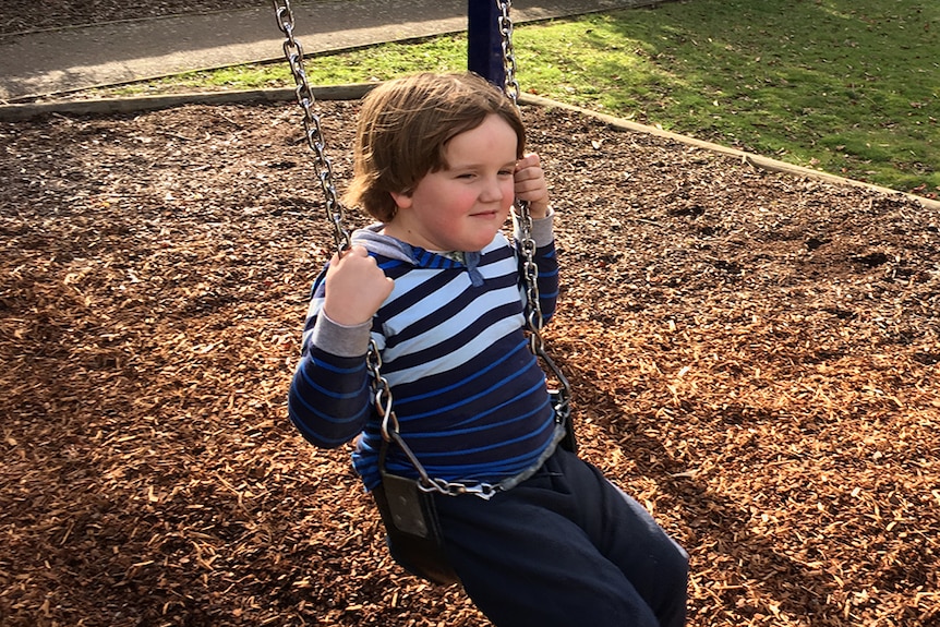 Jake Mitchell sitting on a park swing.