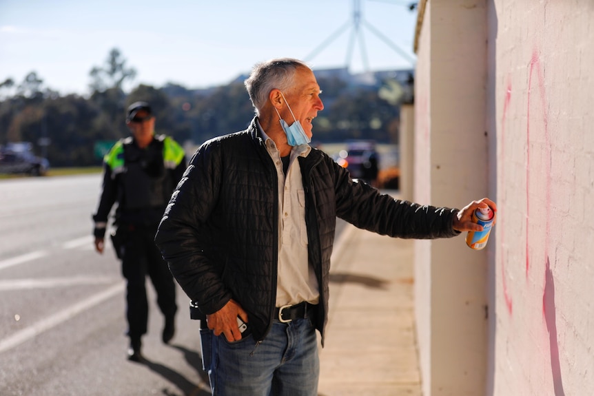 A man sprays red paint on the fence at the lodge 