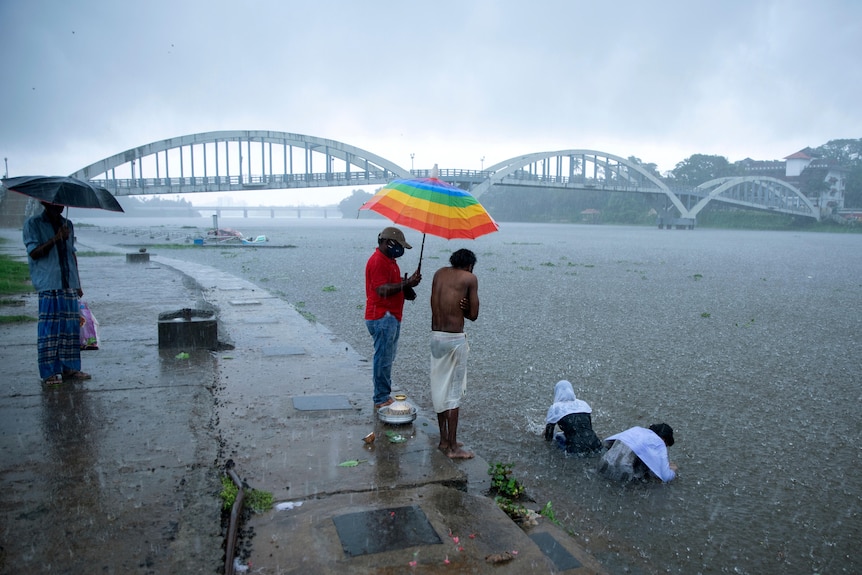 Семья совершает ритуал в реке во время проливного ливня.