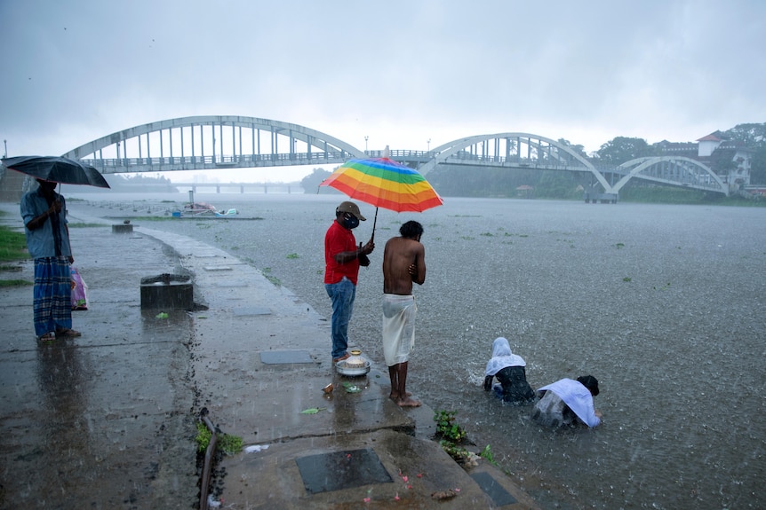 Family performs a ritual in a river during heavy rain