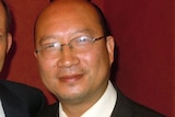 a chinese man in glasses smiling in a suit