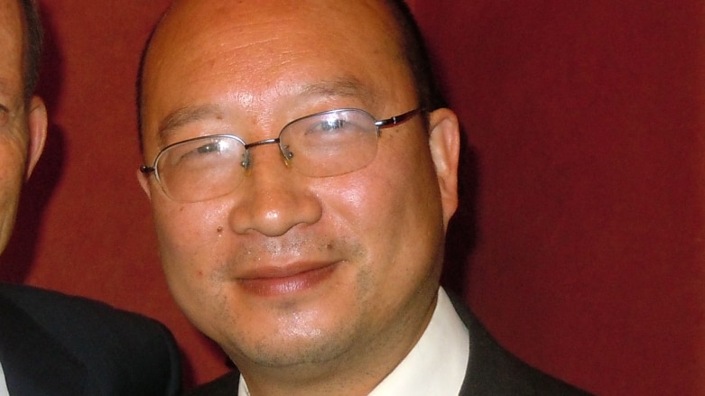 a chinese man in glasses smiling in a suit
