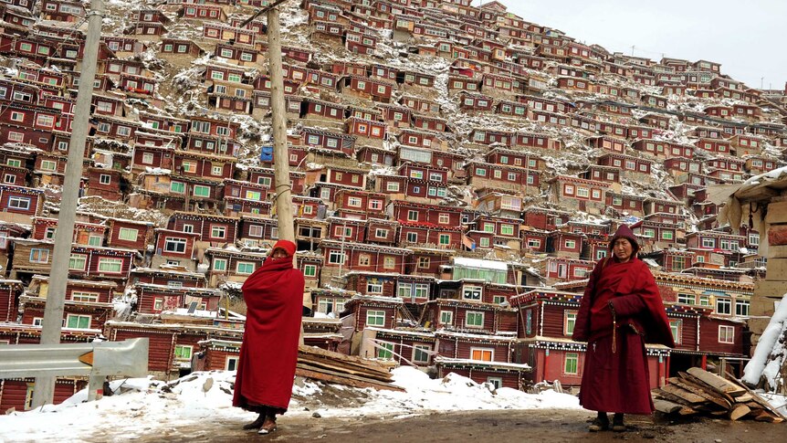 Buddhist monks walking in front of the thousands of small houses at Seda Monastery.