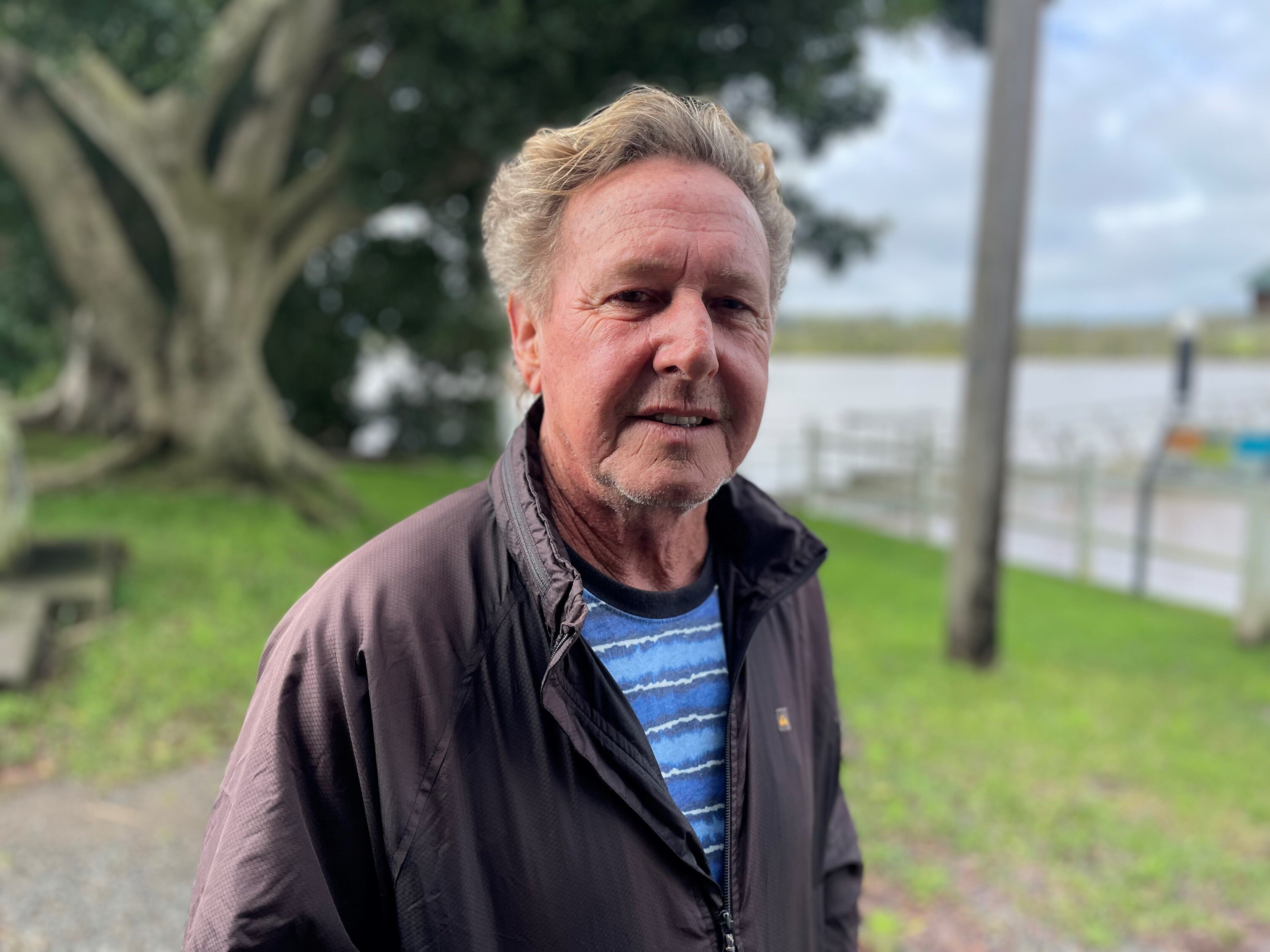 Head shot of man wearing blue striped shirt and black rain jacket
