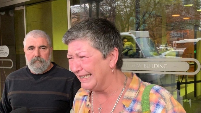 Jo Wynne cries as she is interviewed by reporters outside court, as a man looks on in the background.