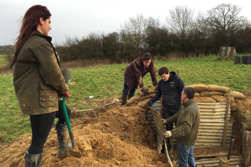 University students watch historian Andrew Robertshaw dig a WW1 trench in Sussex