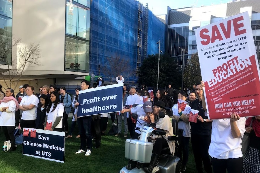 A group of people holding banners stand in front of a building.