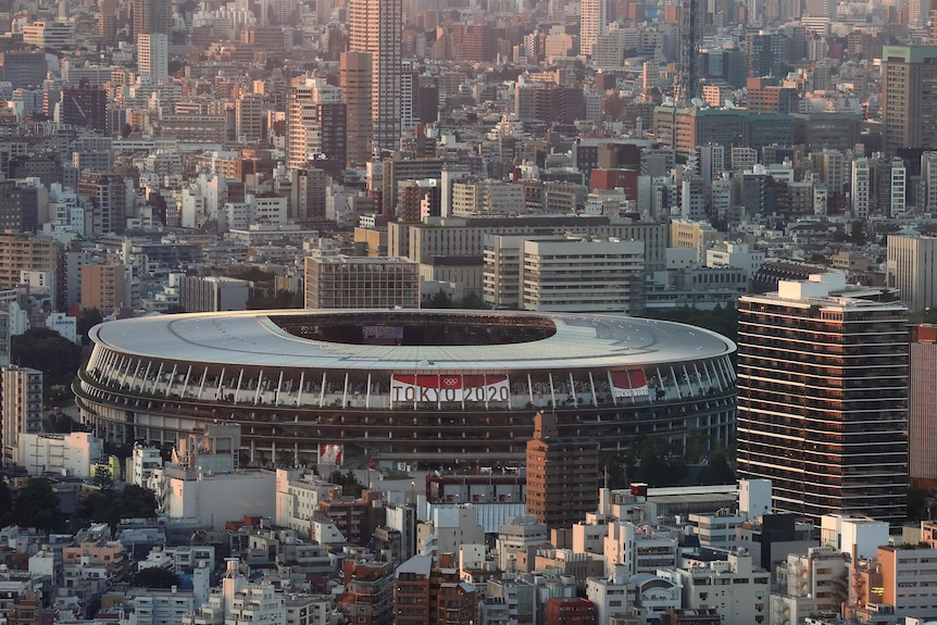 A wide shot of Tokyo showing the Olympic Stadium in the middle of buildings.