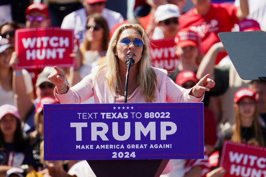 A woman standing behind a podium gestures with her hands