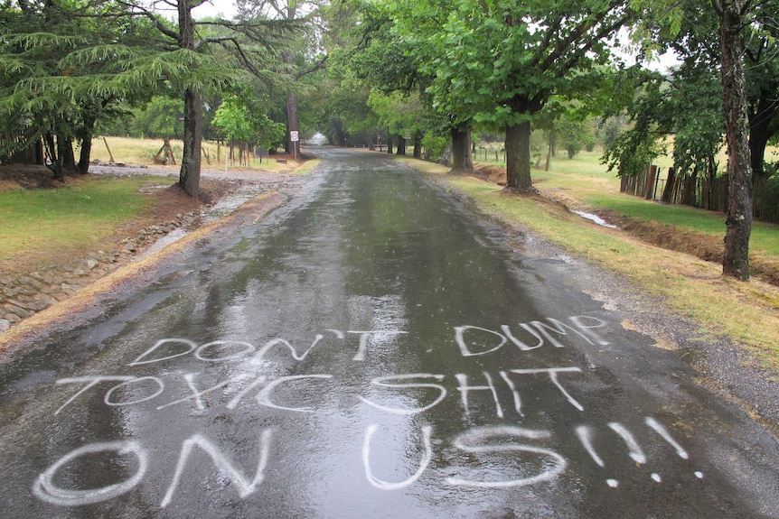 "Don't dump toxic shit on us!!!" is spray painted on a road at Hill End.