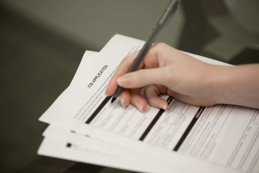 A young woman holding a pen and filling out a job application