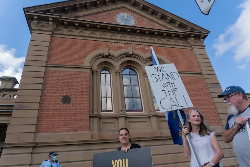 The exterior of a courthouse with a sign reading "we stand with Cali" out the front.