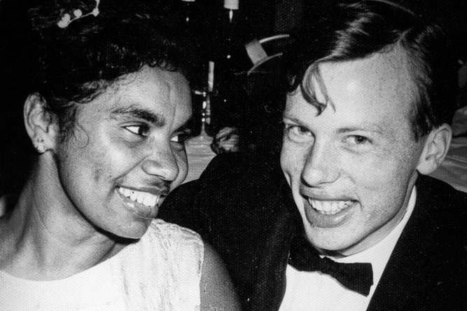 A young couple sitting at a table and smiling.