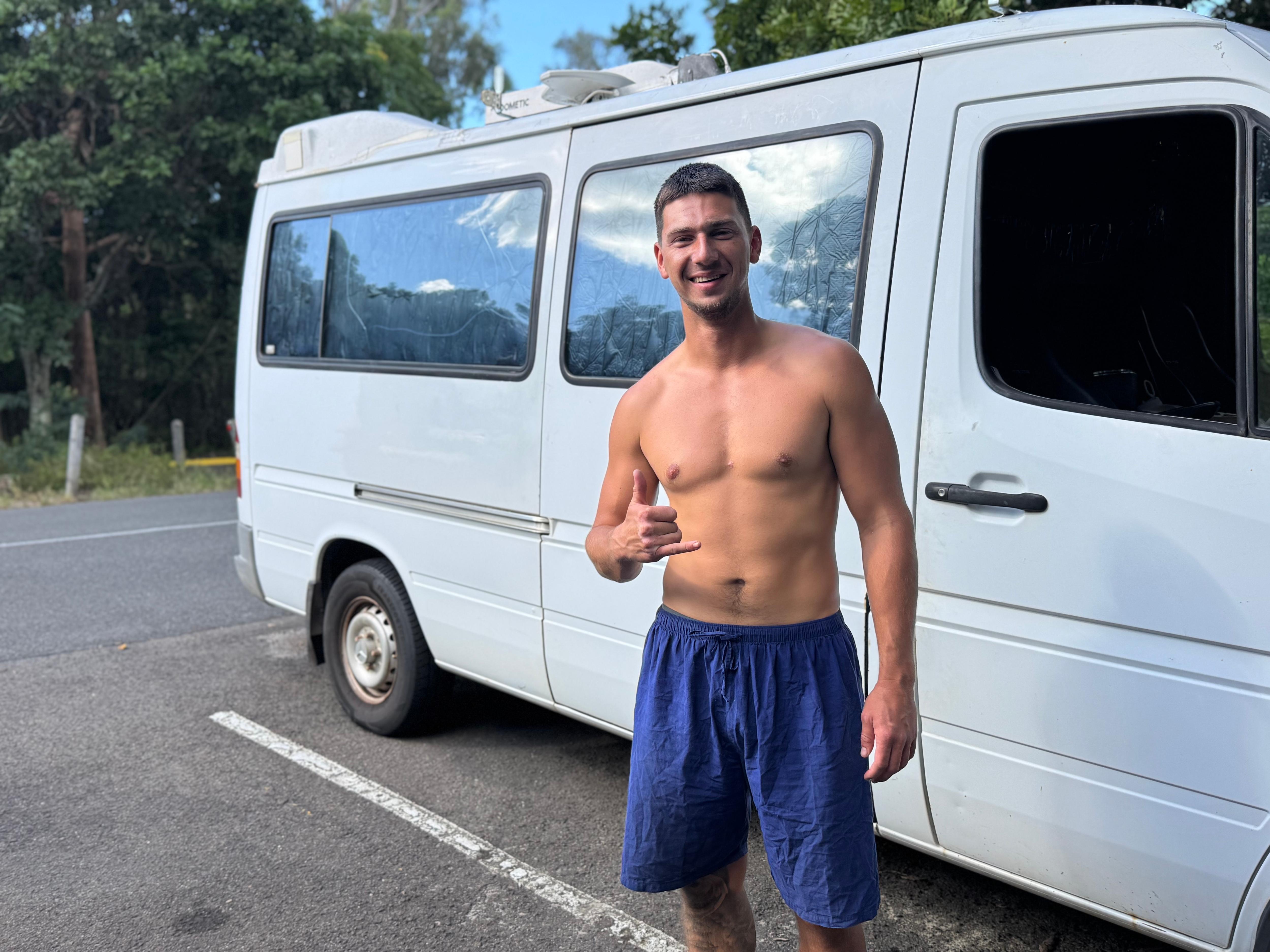 A picture of a young backpacker in front of his van