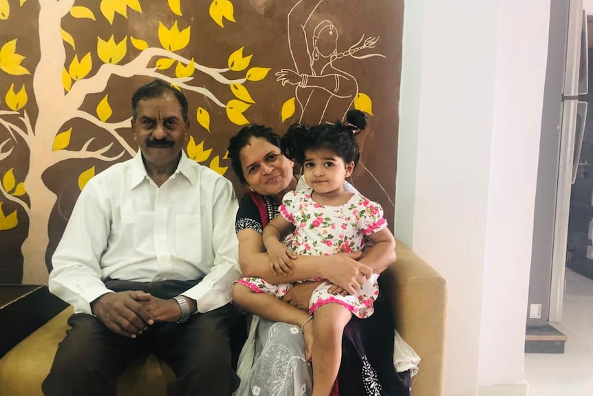Divya's parents holding her toddler-aged daughter in India