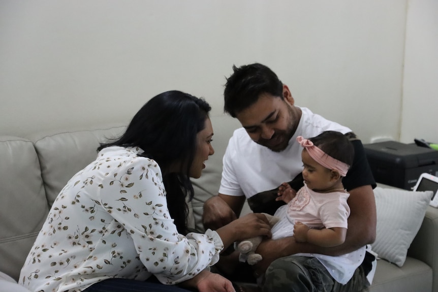 a young family with a baby playing on a couch