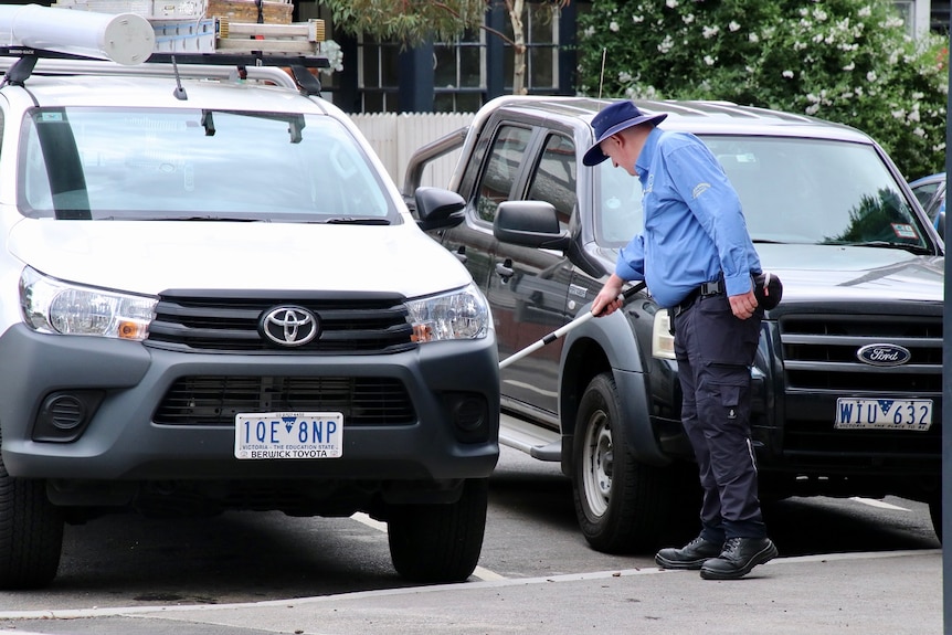 A parking inspector inspects a parked car.