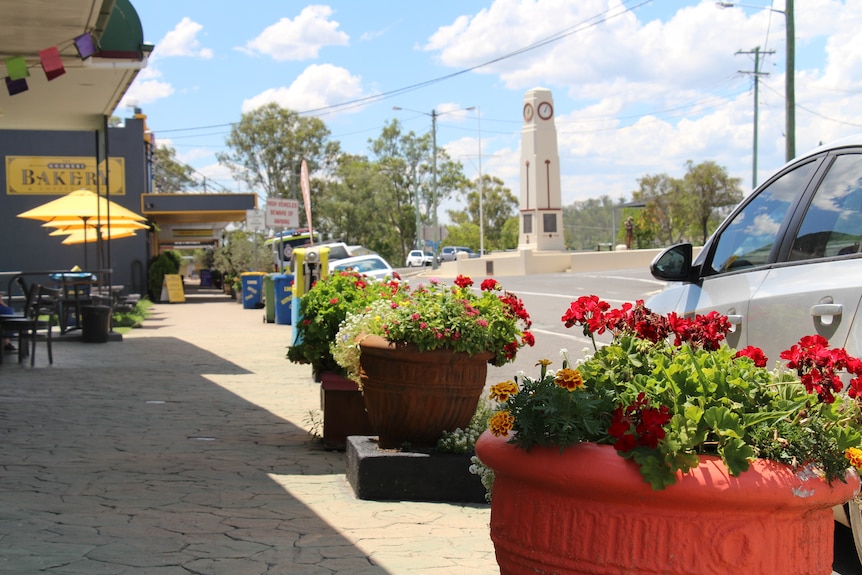 A path down the main street of Goomeri, with flowers in large pots and a war memorial