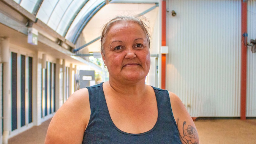 A woman wearing a singlet stands in an empty building.